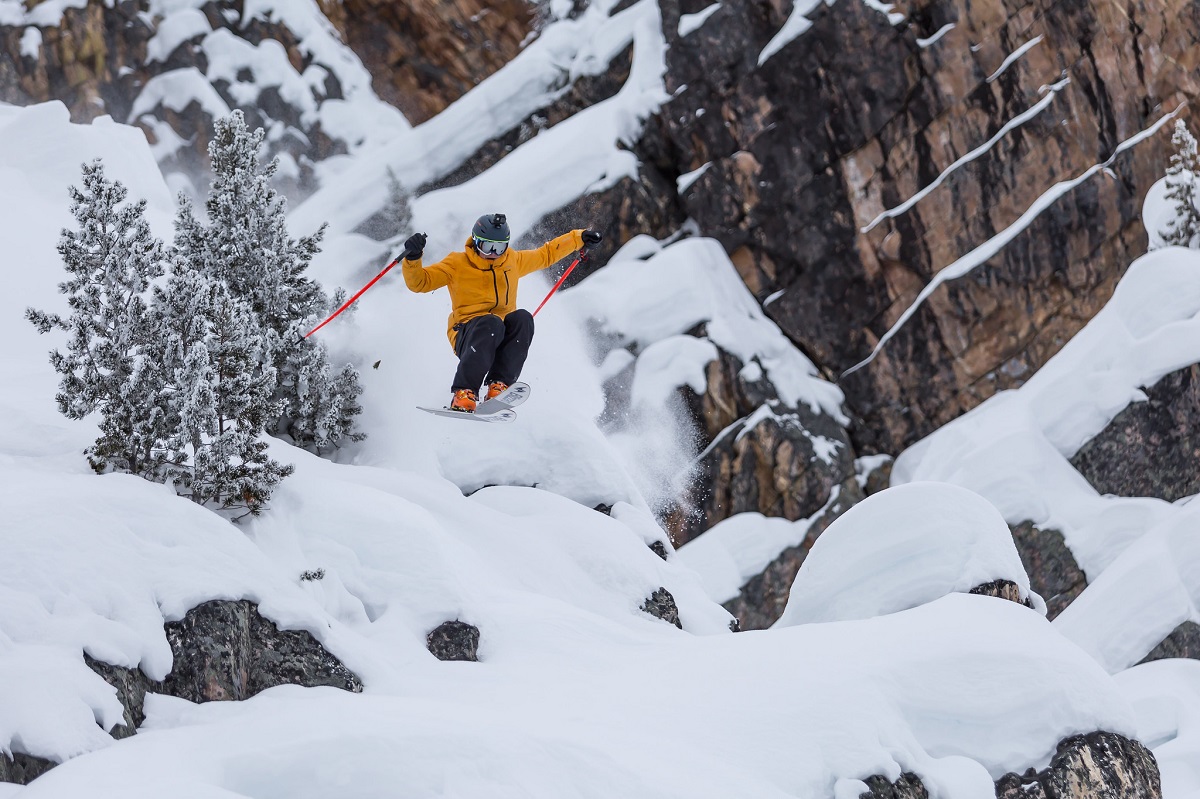 A person jumps off a boulder on skies at Kicking Horse Mountain Resort